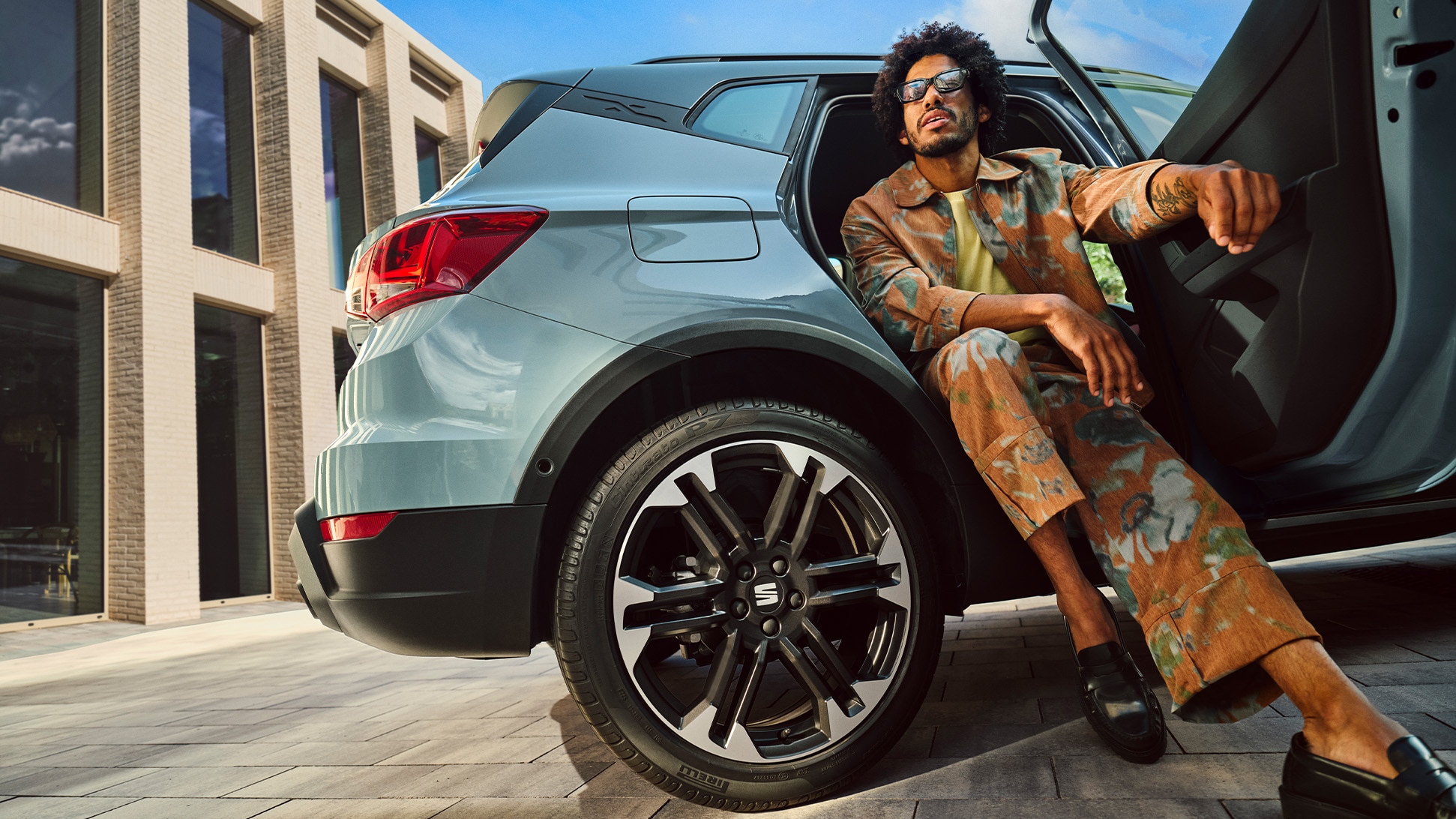 SEAT Arona parked in a modern city setting with the door open and a person sitting casually on the edge