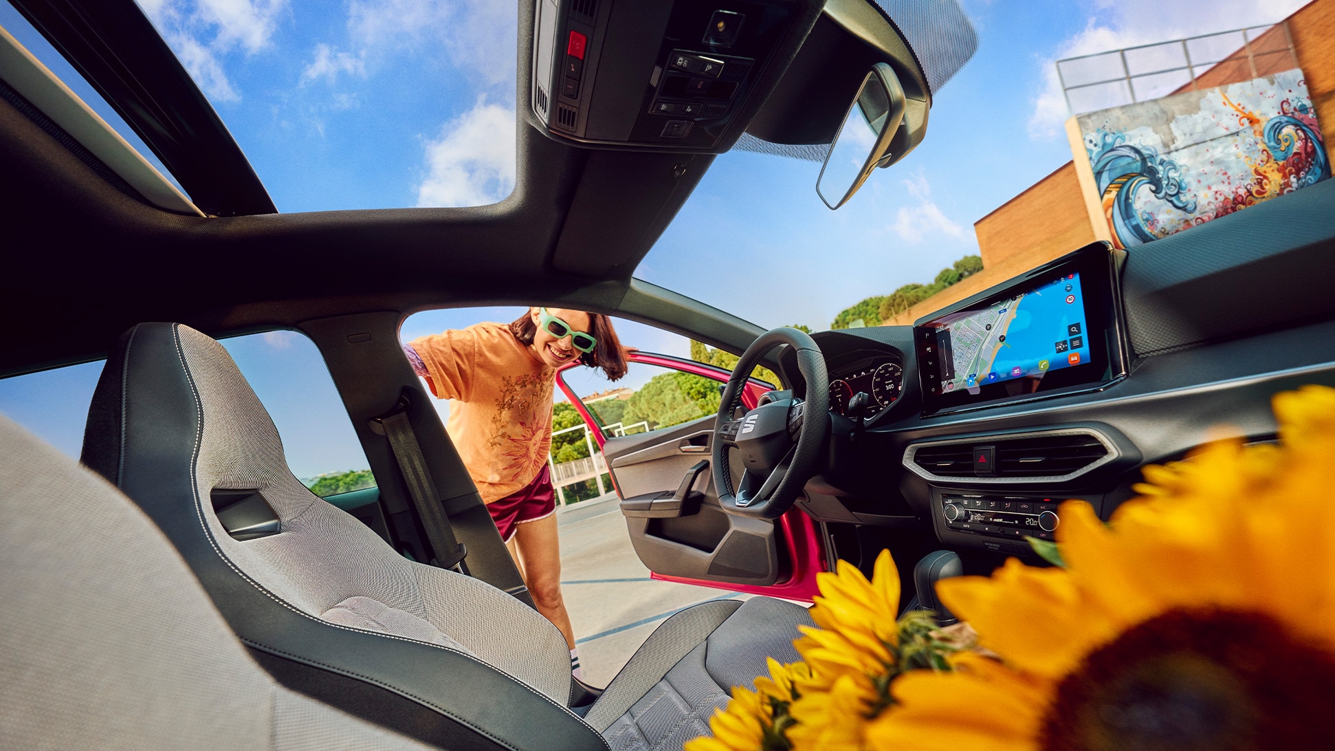 Interior view of SEAT Ibiza showing modern dashboard, touchscreen display and sunroof with a bouquet of sunflowers on the front seat