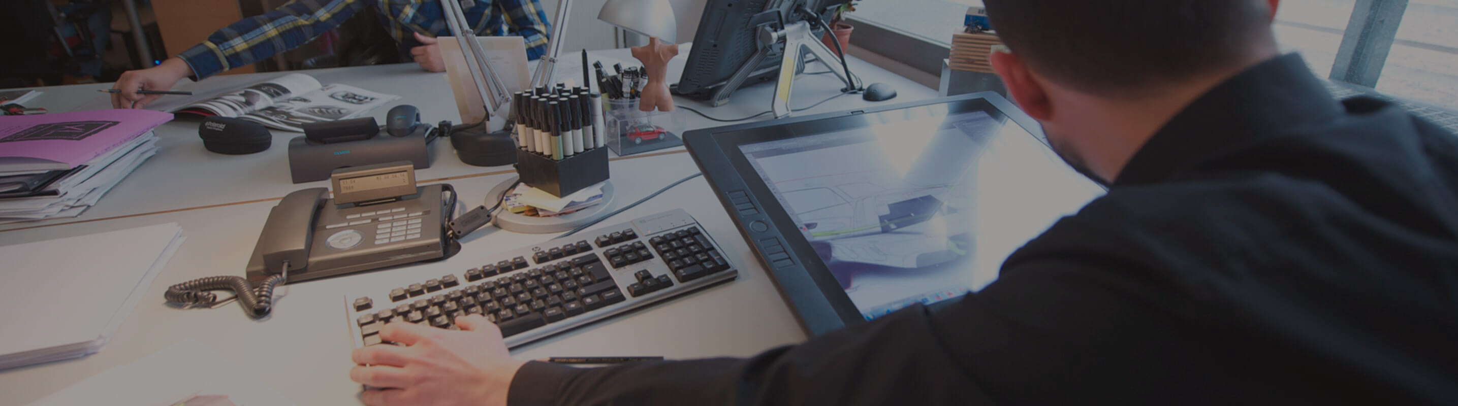 View behind a deak worker’s shoulder with a smart tablet on the desk – SEAT Human Resources